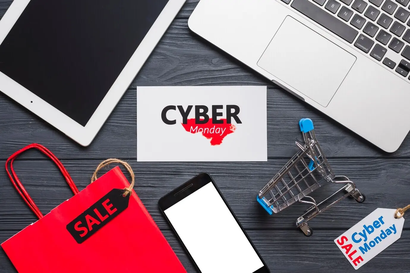 Ноутбук рядом со смартфоном, этикетками, планшетом и пакетом.